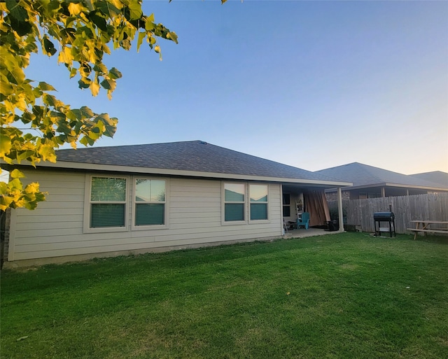 back house at dusk featuring a yard and a patio area