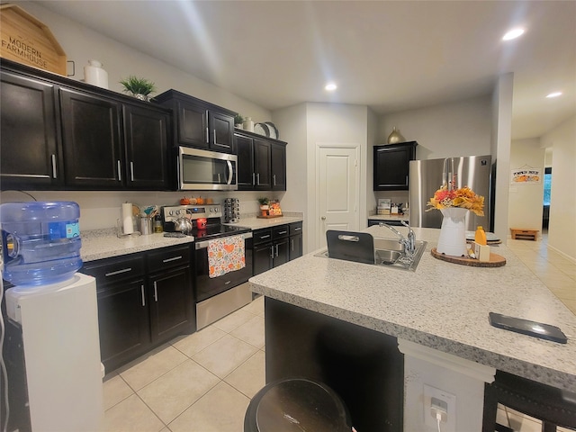 kitchen featuring light tile patterned floors, appliances with stainless steel finishes, sink, and a kitchen breakfast bar