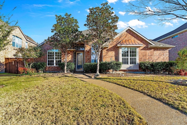 view of front of house featuring a front yard, a standing seam roof, brick siding, and fence