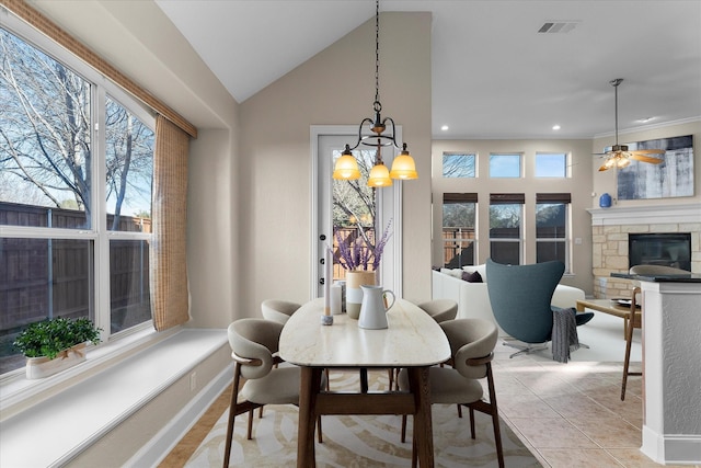 dining area featuring light tile patterned floors, lofted ceiling, a stone fireplace, recessed lighting, and visible vents