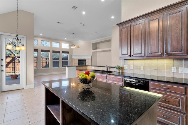 kitchen with a tiled fireplace, dishwasher, open floor plan, dark brown cabinets, and a sink