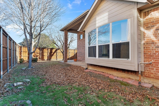 view of side of property with brick siding and a fenced backyard