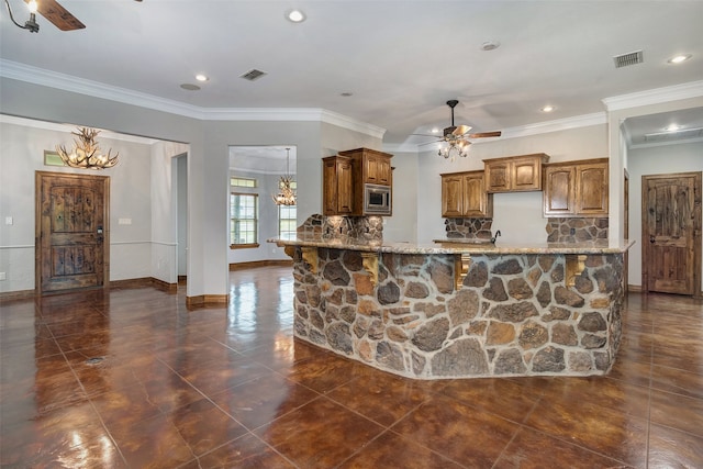 kitchen with backsplash, stainless steel microwave, ornamental molding, light stone countertops, and ceiling fan with notable chandelier