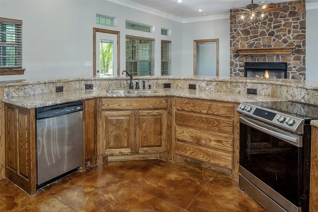 kitchen featuring sink, crown molding, stainless steel appliances, light stone counters, and a stone fireplace