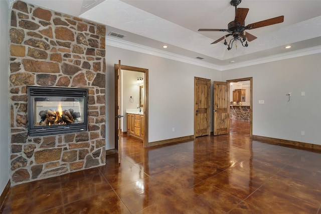 unfurnished living room featuring a stone fireplace, ornamental molding, a raised ceiling, and ceiling fan