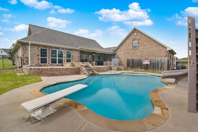 view of swimming pool with a diving board and a patio