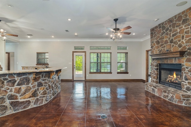 tiled living room featuring crown molding, ceiling fan, and a stone fireplace