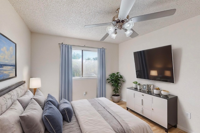 bedroom with light wood-type flooring, ceiling fan, and a textured ceiling