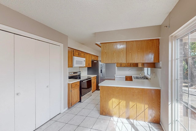 kitchen featuring light tile patterned flooring, sink, kitchen peninsula, a textured ceiling, and appliances with stainless steel finishes