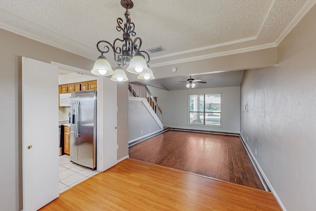 unfurnished dining area featuring light wood-type flooring, ceiling fan with notable chandelier, a textured ceiling, and crown molding