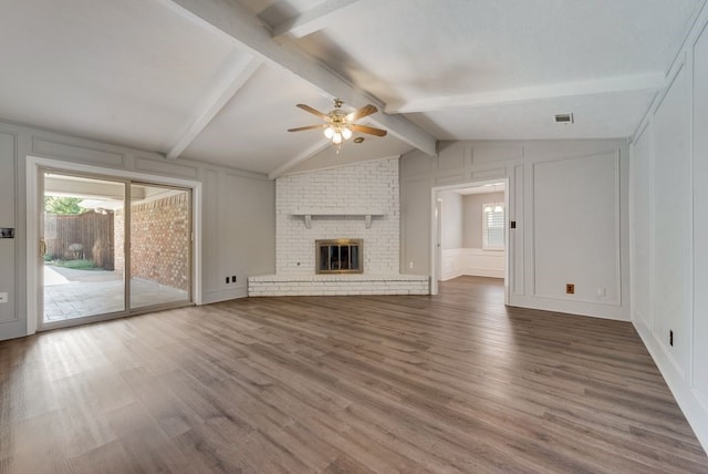 unfurnished living room with a brick fireplace, wood-type flooring, vaulted ceiling with beams, and ceiling fan