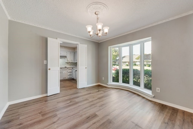 empty room with light hardwood / wood-style flooring, a chandelier, and a textured ceiling