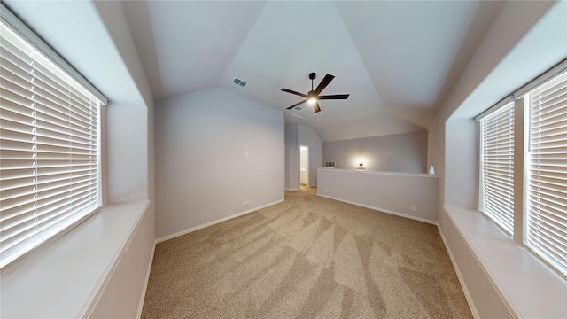 additional living space with light carpet, a wealth of natural light, lofted ceiling, and ceiling fan