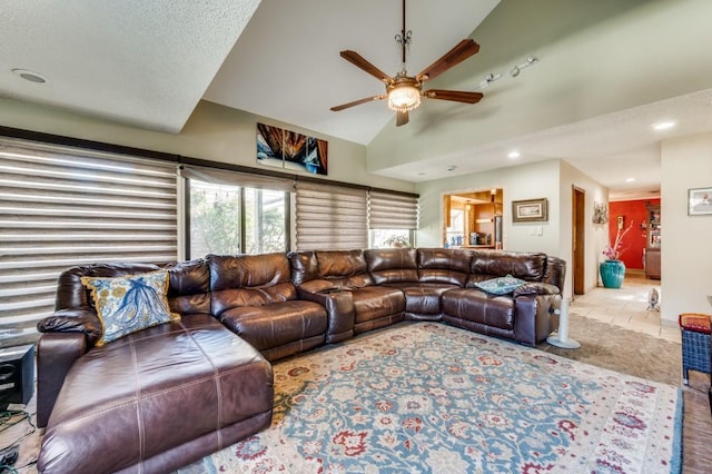 living room with light tile patterned flooring, ceiling fan, lofted ceiling, and a textured ceiling