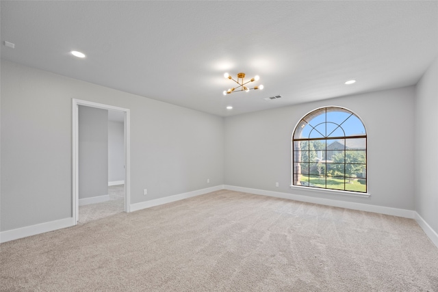 carpeted empty room featuring a chandelier