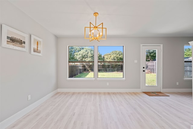 unfurnished dining area with a chandelier and light hardwood / wood-style floors