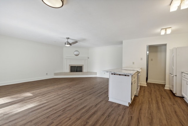 kitchen with white cabinetry, white refrigerator, a tiled fireplace, dark hardwood / wood-style flooring, and a center island