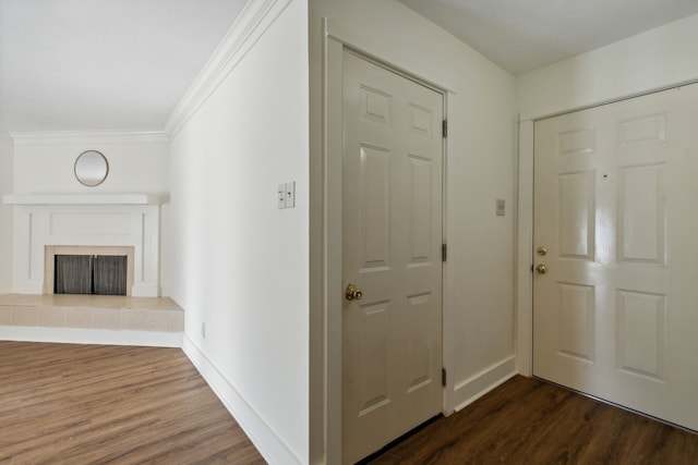 foyer featuring ornamental molding, a tiled fireplace, and dark hardwood / wood-style flooring