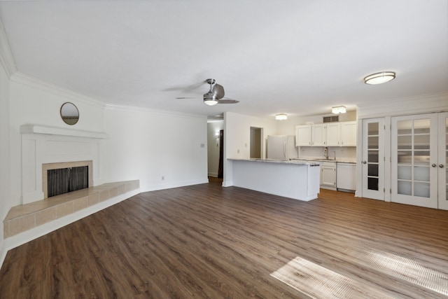 unfurnished living room with ceiling fan, ornamental molding, sink, a tile fireplace, and dark hardwood / wood-style flooring