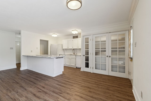 kitchen with white cabinets, dark hardwood / wood-style flooring, white fridge, crown molding, and sink