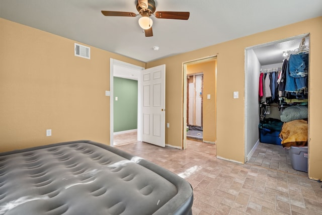 bedroom featuring a closet, ceiling fan, and a walk in closet