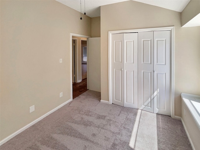 unfurnished bedroom featuring vaulted ceiling, light carpet, and a closet