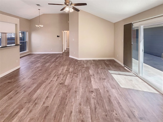 unfurnished living room featuring ceiling fan with notable chandelier, lofted ceiling, and hardwood / wood-style flooring