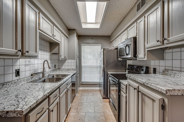 kitchen featuring sink, tasteful backsplash, a textured ceiling, appliances with stainless steel finishes, and light stone countertops