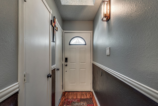 entryway with a skylight, a textured ceiling, and hardwood / wood-style flooring