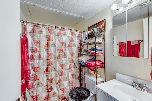 bathroom featuring walk in shower, vanity, toilet, and a textured ceiling