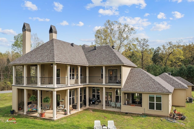 rear view of house with a balcony, a yard, and a patio area