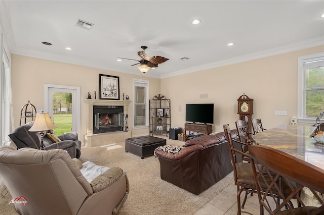 living room featuring a tiled fireplace, ceiling fan, light tile patterned floors, and crown molding