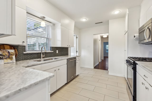 kitchen featuring white cabinets, appliances with stainless steel finishes, hanging light fixtures, and sink