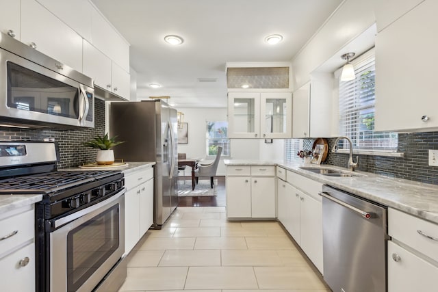 kitchen featuring white cabinets, sink, light hardwood / wood-style flooring, decorative backsplash, and stainless steel appliances