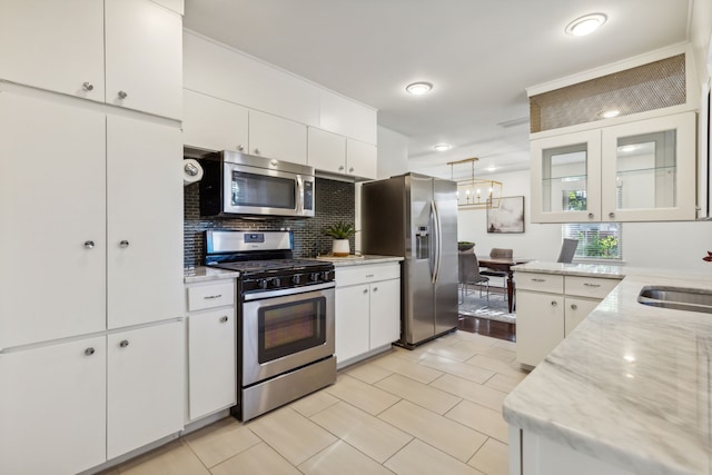 kitchen featuring white cabinets, hanging light fixtures, and appliances with stainless steel finishes