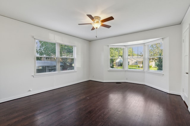 unfurnished room featuring ceiling fan, dark wood-type flooring, and a wealth of natural light