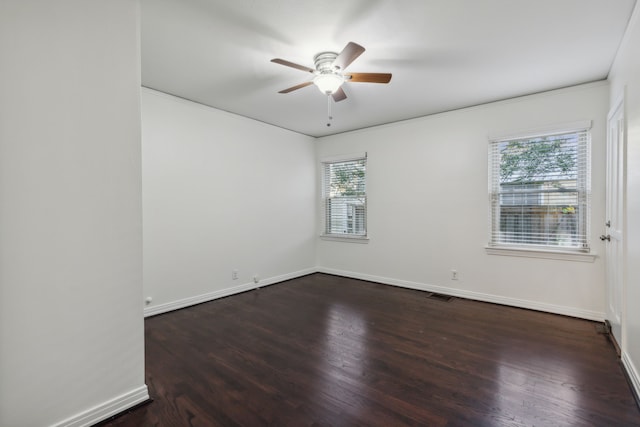 empty room featuring a wealth of natural light, dark hardwood / wood-style flooring, and ceiling fan