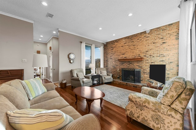 living room featuring dark hardwood / wood-style flooring, a textured ceiling, a brick fireplace, ornamental molding, and brick wall