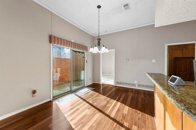 unfurnished dining area featuring ornamental molding, dark wood-type flooring, a textured ceiling, and a chandelier