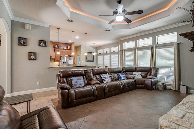 tiled living room featuring a raised ceiling, ornamental molding, and a healthy amount of sunlight