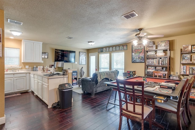 dining room with a textured ceiling, ceiling fan, and dark wood-type flooring