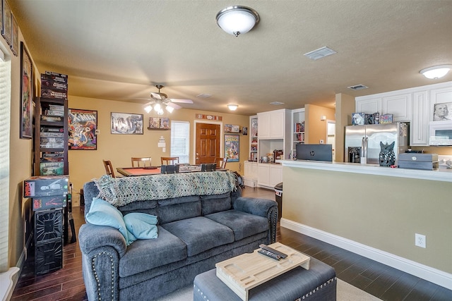 living room with ceiling fan, dark hardwood / wood-style floors, and a textured ceiling