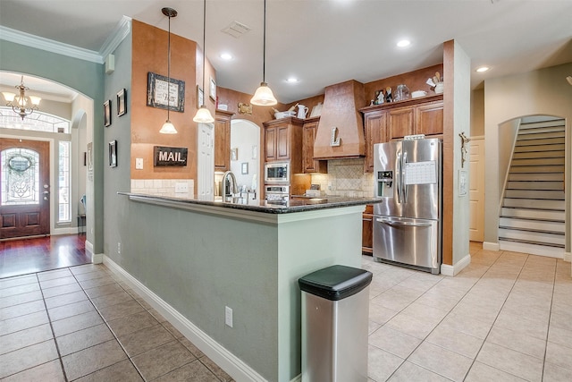 kitchen with kitchen peninsula, crown molding, stainless steel appliances, light tile patterned floors, and decorative light fixtures