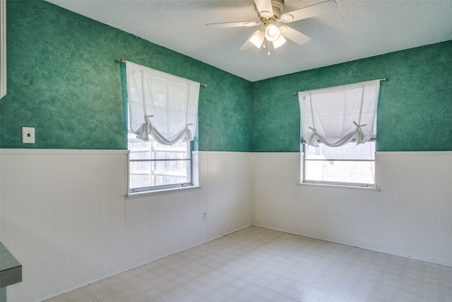 empty room featuring a textured ceiling, a healthy amount of sunlight, and ceiling fan