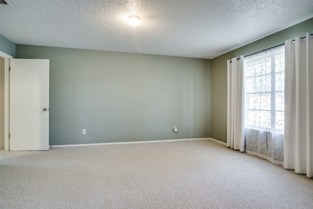 carpeted spare room featuring a textured ceiling and a healthy amount of sunlight