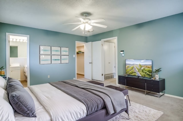 bedroom featuring a textured ceiling, ensuite bathroom, and ceiling fan