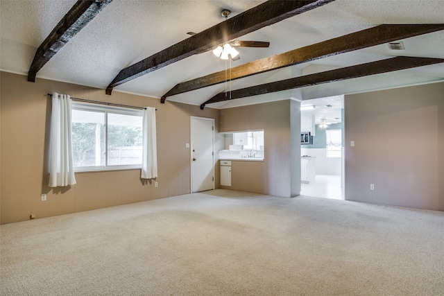 unfurnished living room featuring sink, lofted ceiling with beams, carpet flooring, a textured ceiling, and ceiling fan