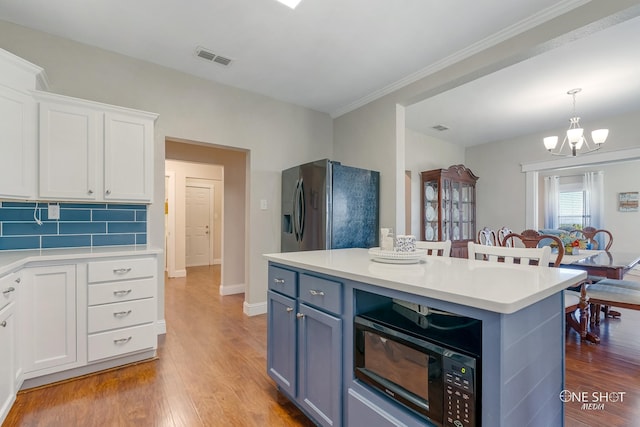 kitchen with stainless steel fridge, tasteful backsplash, white cabinetry, a center island, and hardwood / wood-style floors