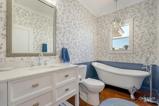 bathroom with a bathing tub, vanity, an inviting chandelier, hardwood / wood-style flooring, and toilet