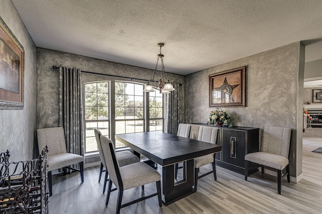 dining area with a textured ceiling, hardwood / wood-style floors, and a chandelier